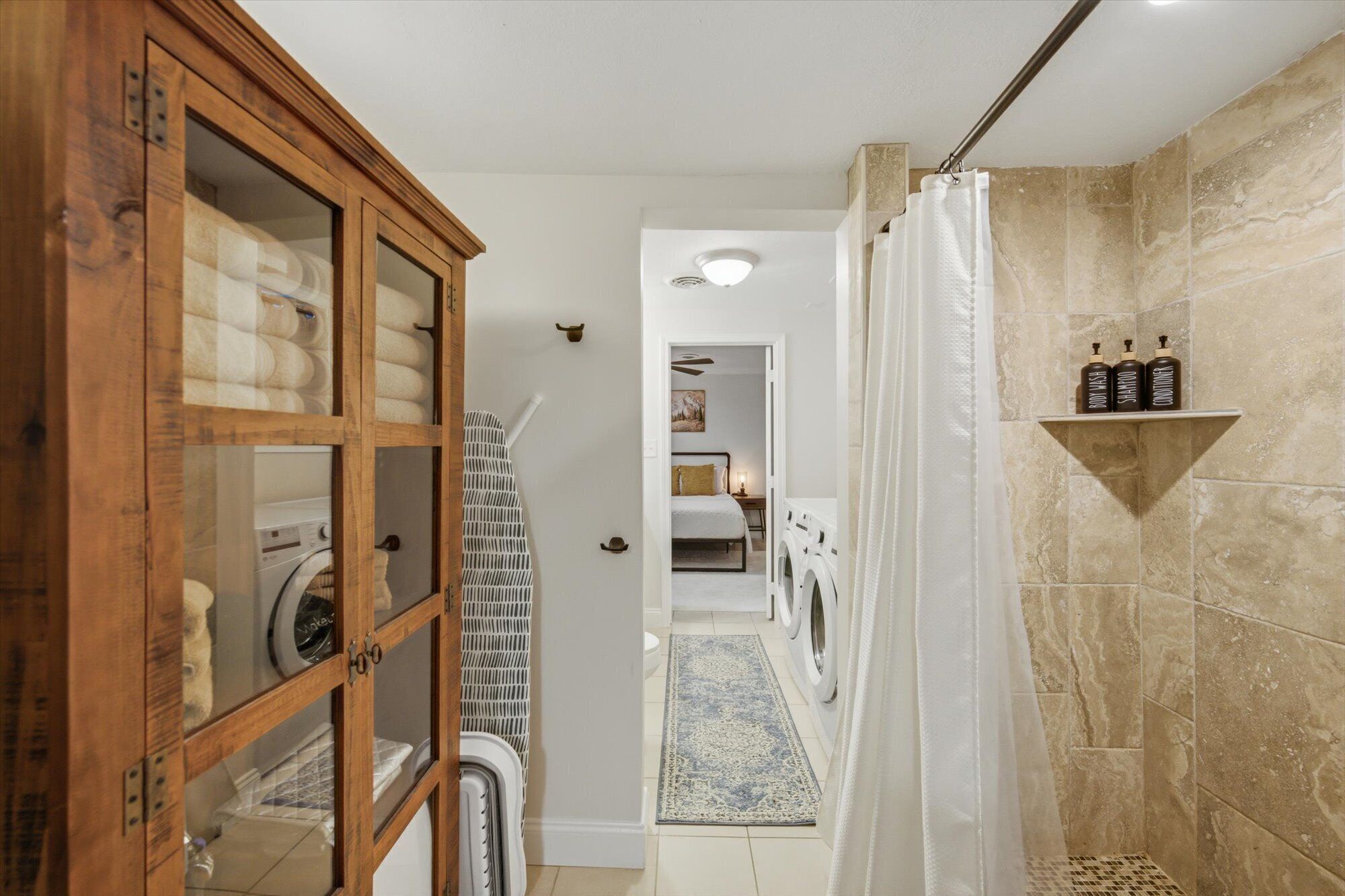 Une buanderie équipée d’un lave-linge, d’un sèche-linge et d’un meuble en bois doté de portes en verre.