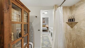 Une buanderie équipée d’un lave-linge, d’un sèche-linge et d’un meuble en bois doté de portes en verre.