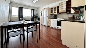 Une cuisine de taille réduite, avec des meubles de rangement en bois, une table à manger et des chaises, et une vue par la fenêtre.