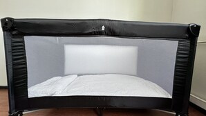 Un objet noir, à quatre pieds, de forme rectangulaire, doté d’une grille en treillis au centre, posé sur un plancher en bois.