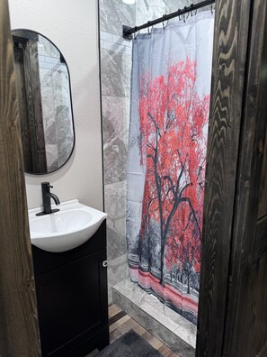 A bathroom with a white sink, black cabinet, and a shower curtain with a red tree design. - Hit the trail from the property! Game room, fire pit and 4 king suites (Muse)