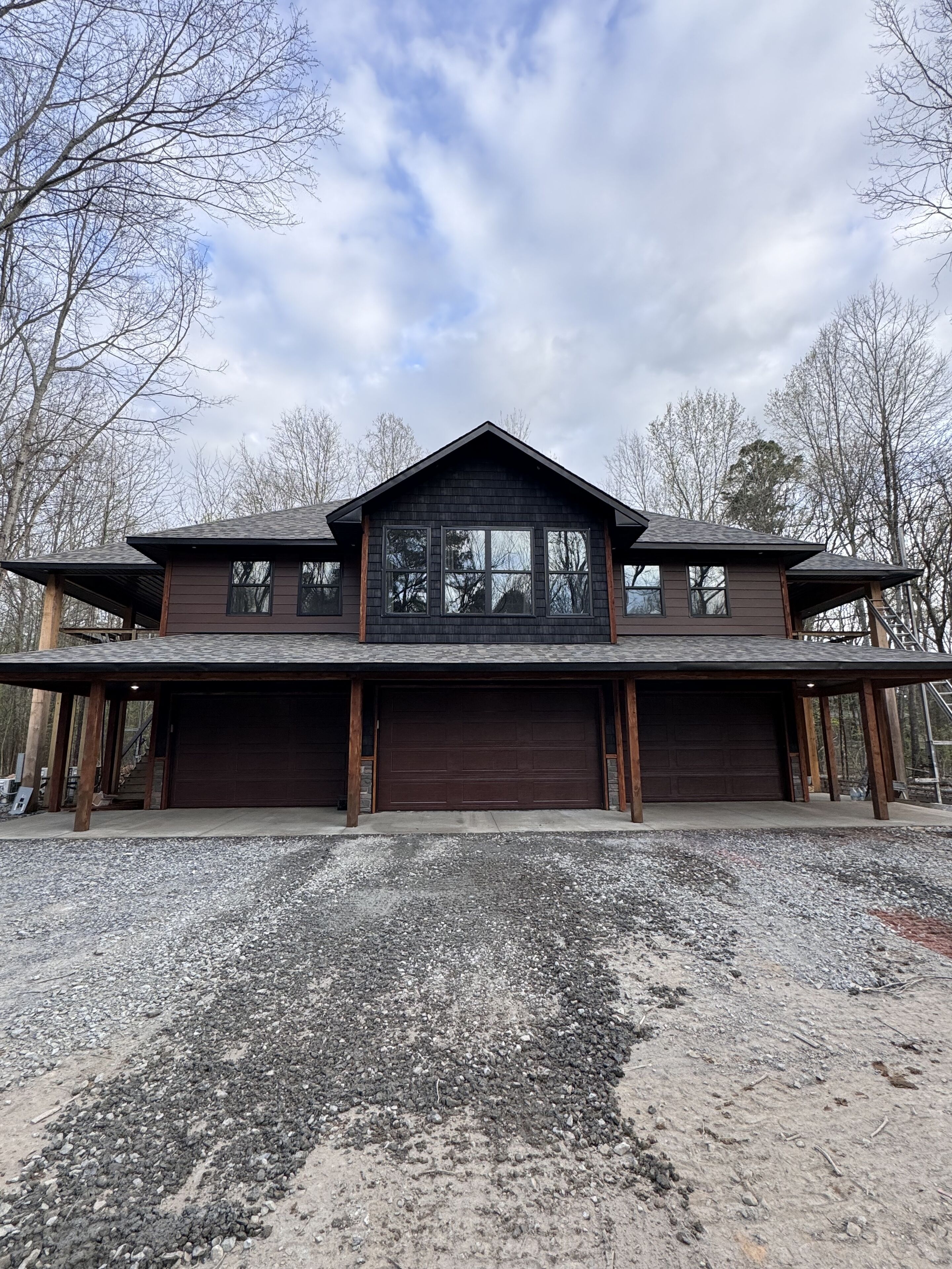 Une grande maison moderne à deux étages, dotée d’un garage imposant et d’une allée couverte.