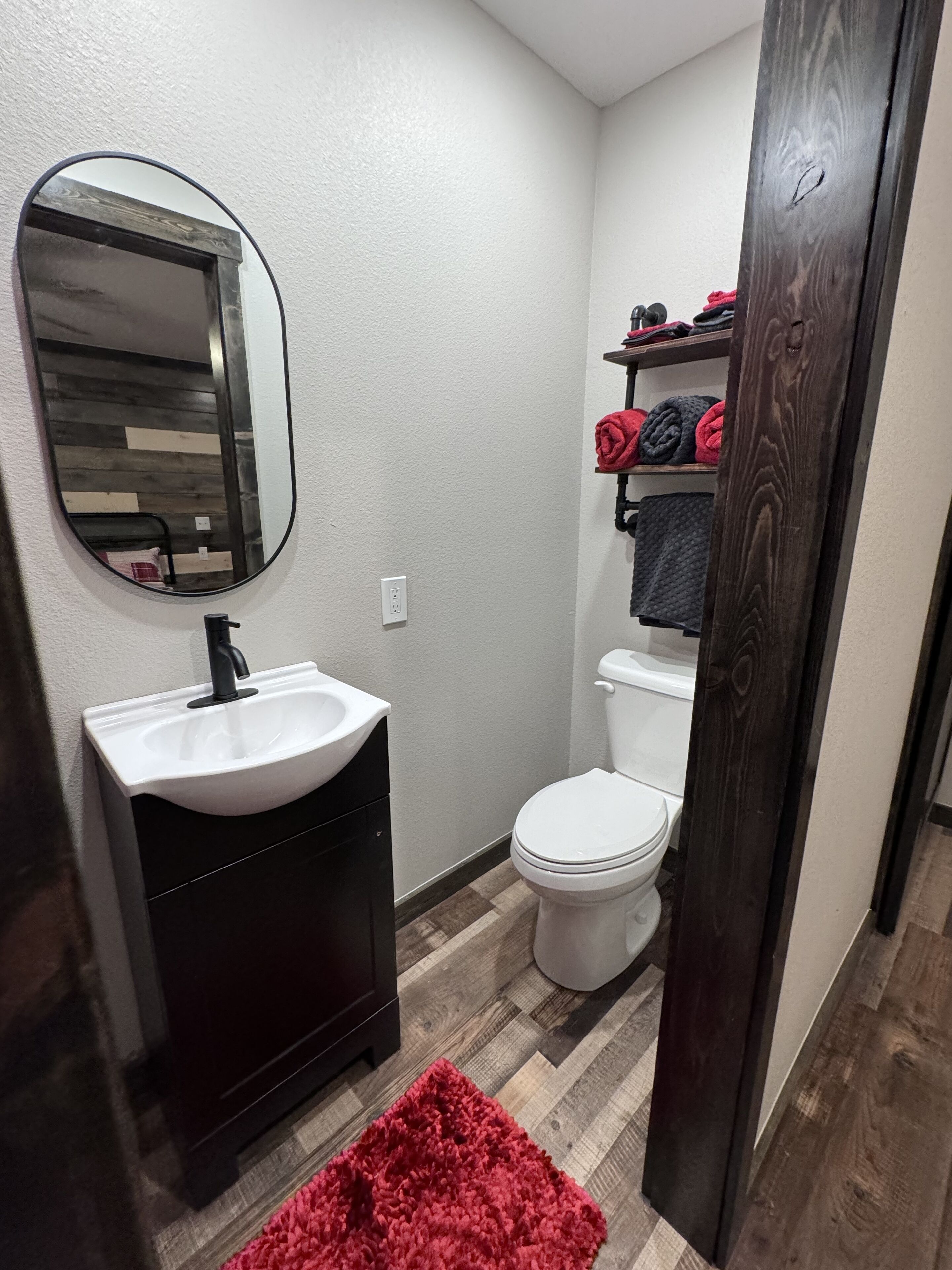 A compact bathroom with a white sink, a toilet, and a mirror.