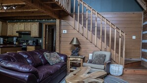 A cozy interior with a wooden staircase, leather sofa, and a dining area. - A~Bears Den- Pet Friendly, Hot Tub, 2 King Suites, Minutes to GSMNP! (Townsend)