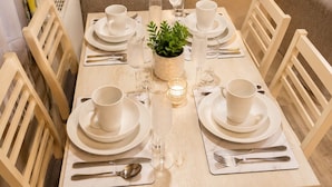 A dining table set for six with white plates, cups, and cutlery, surrounded by wooden chairs. - Bird Lake Pastures 2 Bedrooms 2 Baths  (Northampton)