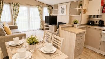 A modern apartment with a dining area, kitchen, living room, and a TV.