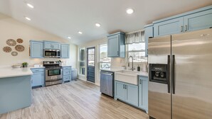 Una cocina moderna con armarios azul claro, electrodomésticos de acero inoxidable y una isla central.