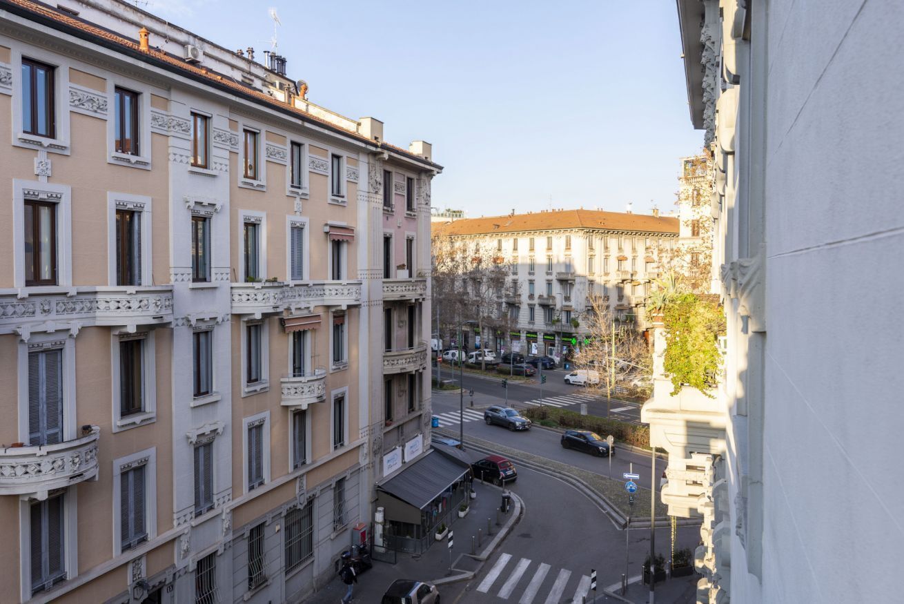 Ein mehrstöckiges Gebäude mit Balkonen, Blick auf eine Straße und geparkten Autos.