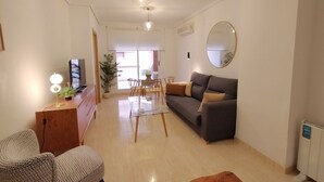 Una sala de estar moderna con un sofá, una mesa de comedor y un televisor.