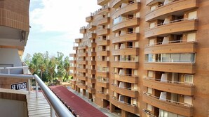 Un edificio residencial de varios pisos con balcones, un toldo rojo y un cartel que indica 