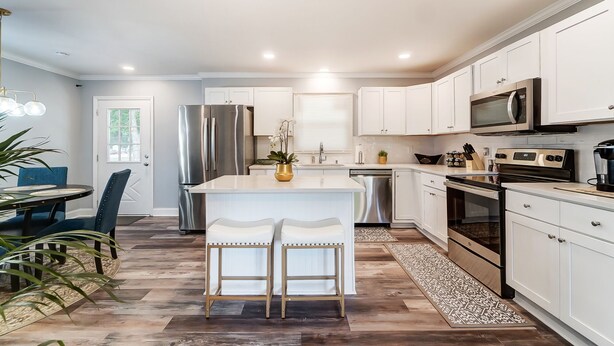 A modern kitchen with white cabinetry, stainless steel appliances, and a central island with bar stools. - Charlotte Pet Friendly 3BR Chateau • Hot Tub • Mini Golf • Fire Pit • SouthPark (Charlotte)