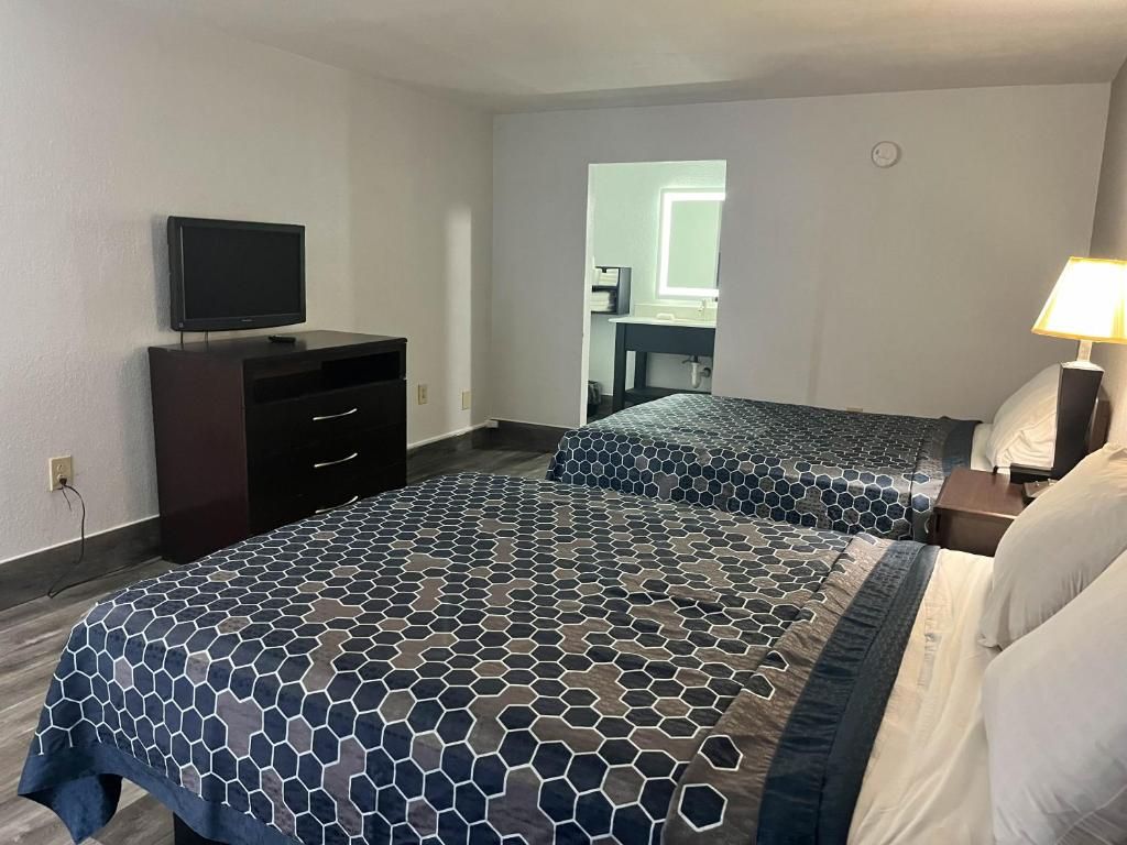 Habitación de hotel con cama, televisión, escritorio y lámpara.