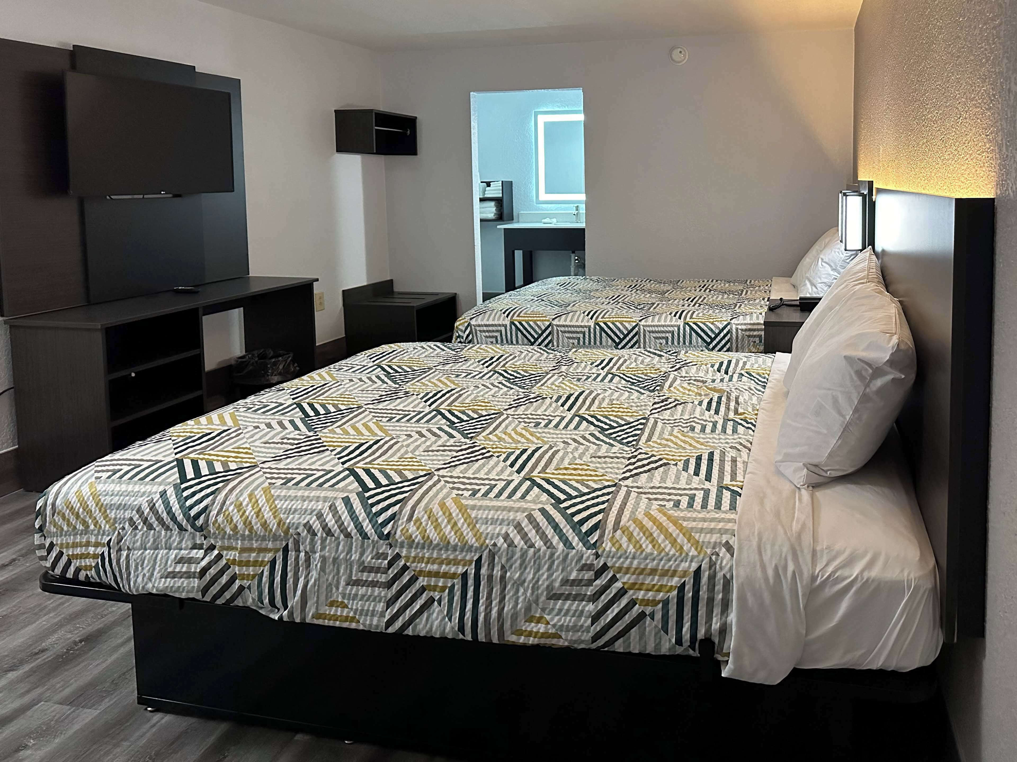 A hotel room with a bed, a TV, a desk, and a window.