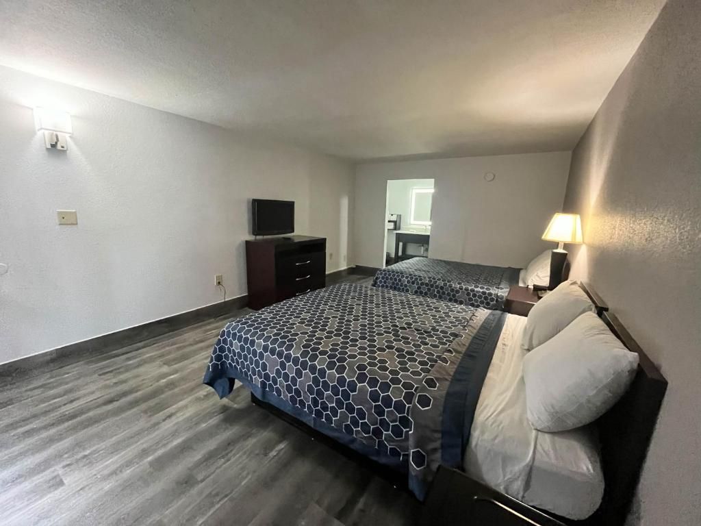 Habitación de hotel con una cama, un escritorio, una silla, una lámpara y un televisor.