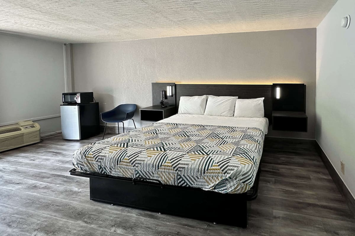 Een moderne hotelkamer met een bed, nachtkastjes, een stoel, een bureau en een verwarming.