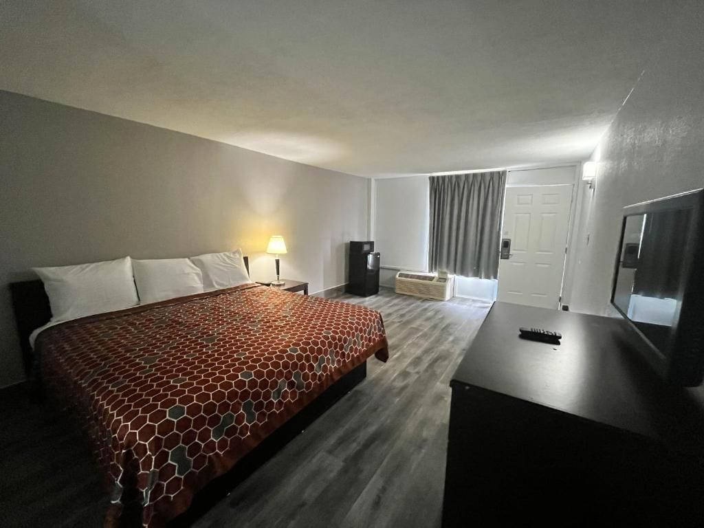 A hotel room with a bed, a desk, a television, and a window with curtains.