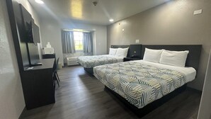 Une chambre d’hôtel avec deux lits, un bureau avec un ordinateur, un miroir et une fenêtre avec des rideaux.