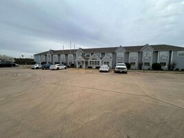 A multi-story building with a parking lot in front.