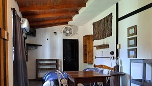 A cozy room with a wooden ceiling, a bed with a blue and white duvet, a wooden table, and two white chairs.
