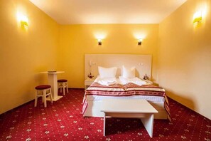 A hotel room with a bed, bedside tables, and a small desk with two chairs. - Hotel Extravagance (Sighisoara)