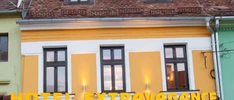 A hotel with a yellow facade and a sign that reads "HOTEL EXTRAVAGANCE RESTAURANT".
