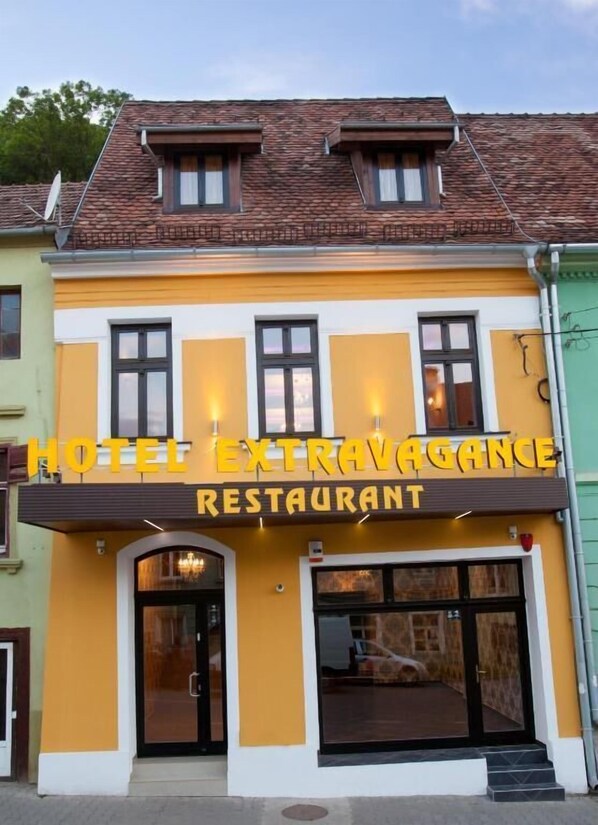 A hotel with a yellow facade and a sign that reads "HOTEL EXTRAVAGANCE RESTAURANT". - Hotel Extravagance (Sighisoara)