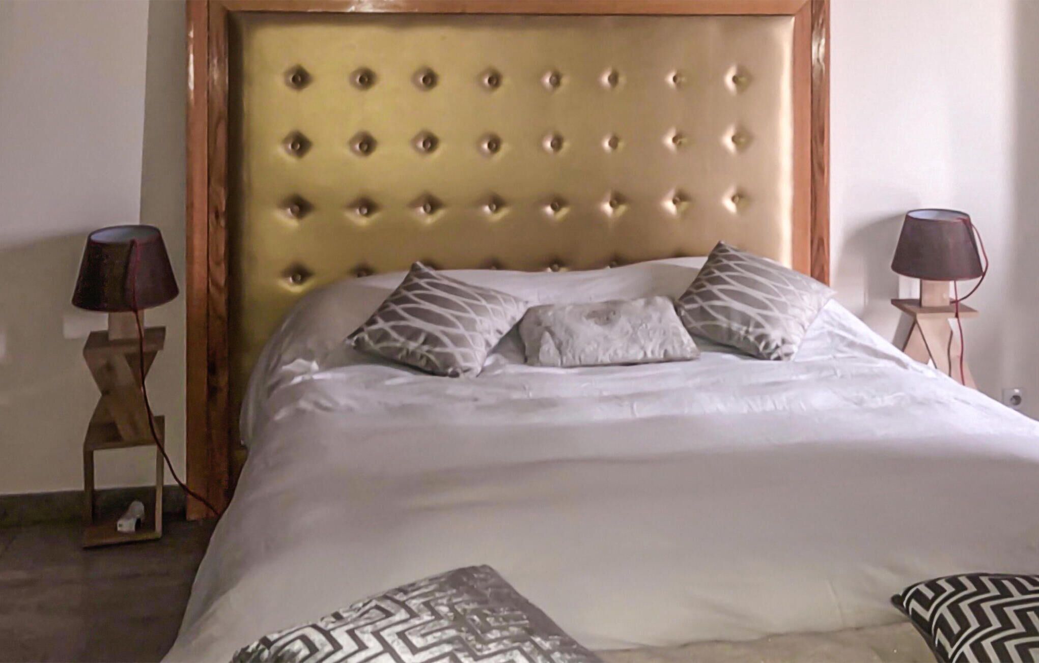 A neatly made bed with a tufted headboard, two bedside lamps, and patterned pillows.