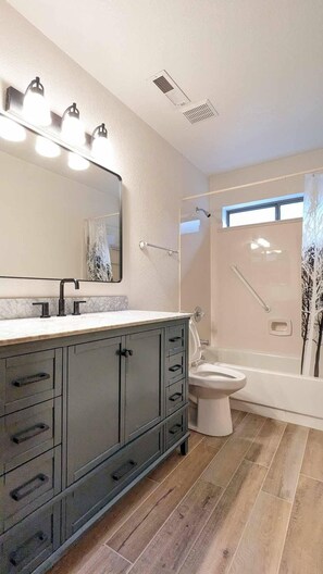 Un baño moderno con un amplio tocador, inodoro y zona de ducha.