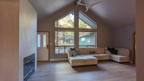 Un salón amplio con techo alto, ventanas grandes, ventilador de techo y un sofá modular.
