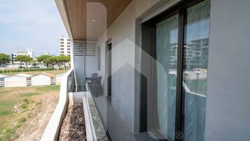 Ein moderner Balkon mit Holzboden, Glasdoor und Blick auf die Stadt.