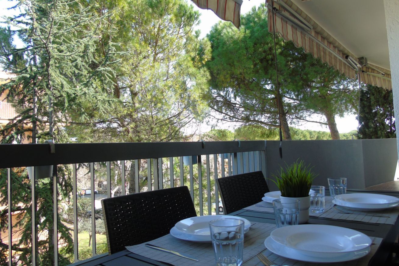 Un balcon avec une table dressée pour le repas, des chaises et une plante en pot.