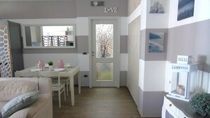 A modern living room with a sofa, a dining table, and a kitchen area.