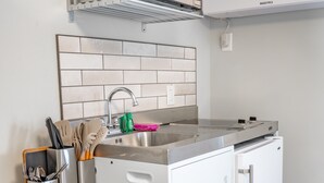 A compact kitchen with a stainless steel sink, a microwave, and an oven. - Cozy second floor suite with kitchenette! (Hampton)