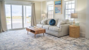 A living room with a sofa, a coffee table, and a side table with lamps. - Gorgeous Oceanfront Suite! (Hampton)