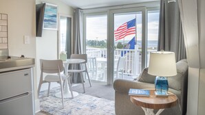 Ein Hotelzimmer mit Küchenzeile, einer Essecke mit Stühlen und Tisch, einer Couch mit Lampe und einem Balkon mit einer US-amerikanischen Flagge.