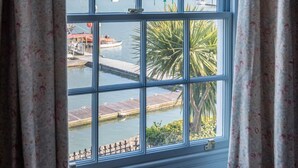A window with a view of a harbor, including boats and a dock. - Lifeboat Cottage -  a cottage that sleeps 2 guests  in 1 bedroom (Salcombe)