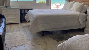 A bedroom with a large bed, a nightstand, a dresser, and a view of the beach. - Beachfront, clean, quiet, luxury condo on 3 rd fl amazing view! Walk to Tootsies (Panama City Beach)
