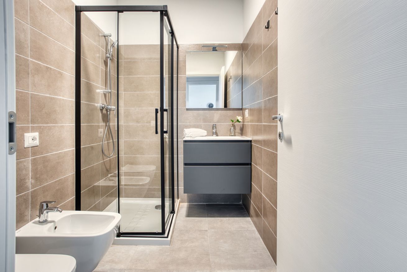 A modern bathroom with a glass shower enclosure, a sink, and a vanity with drawers.