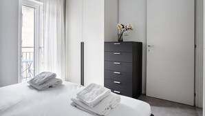 Ein Schlafzimmer mit einem Bett, einem Schminktisch, einer Tür und einem Fenster mit Vorhängen.