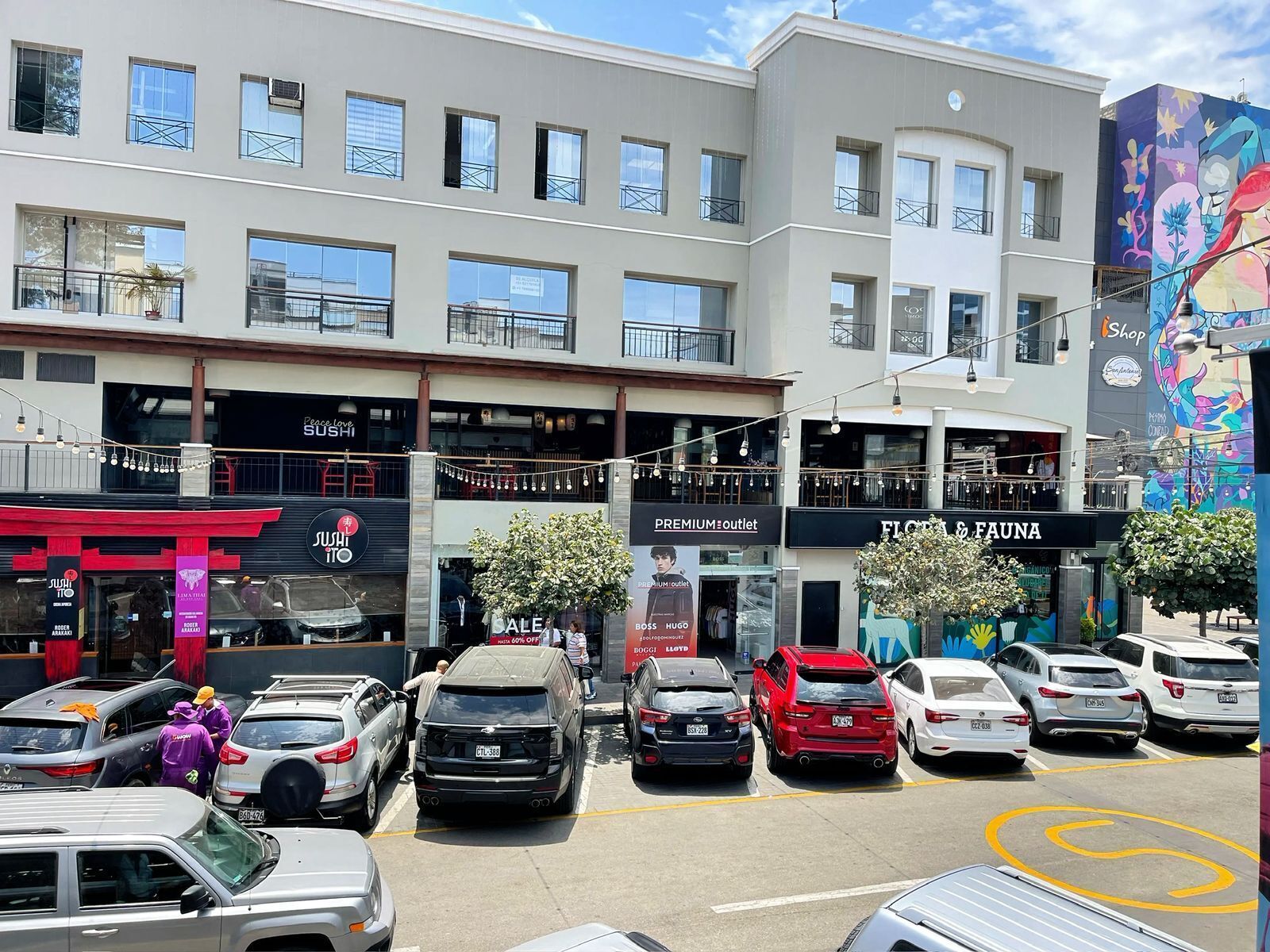 Ein mehrstöckiges Gebäude mit verschiedenen Geschäften, darunter ein Sushi-Restaurant, ein Premium Outlet und ein Blumen- und Tiergeschäft.