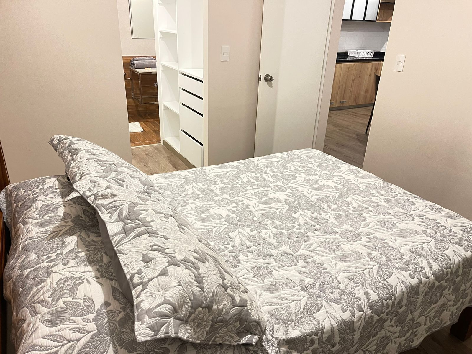 Una camera da letto con un letto, un armadio e un bagno parzialmente visibile attraverso una porta aperta.