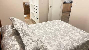 Una camera da letto con un letto, un armadio e un bagno parzialmente visibile attraverso una porta aperta.