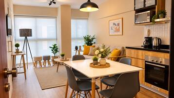 A modern kitchen with a dining area, wooden cabinets, a black oven, and a large window providing natural light.
