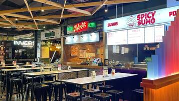 A restaurant with multiple seating areas, a pizza counter, and a sushi counter.