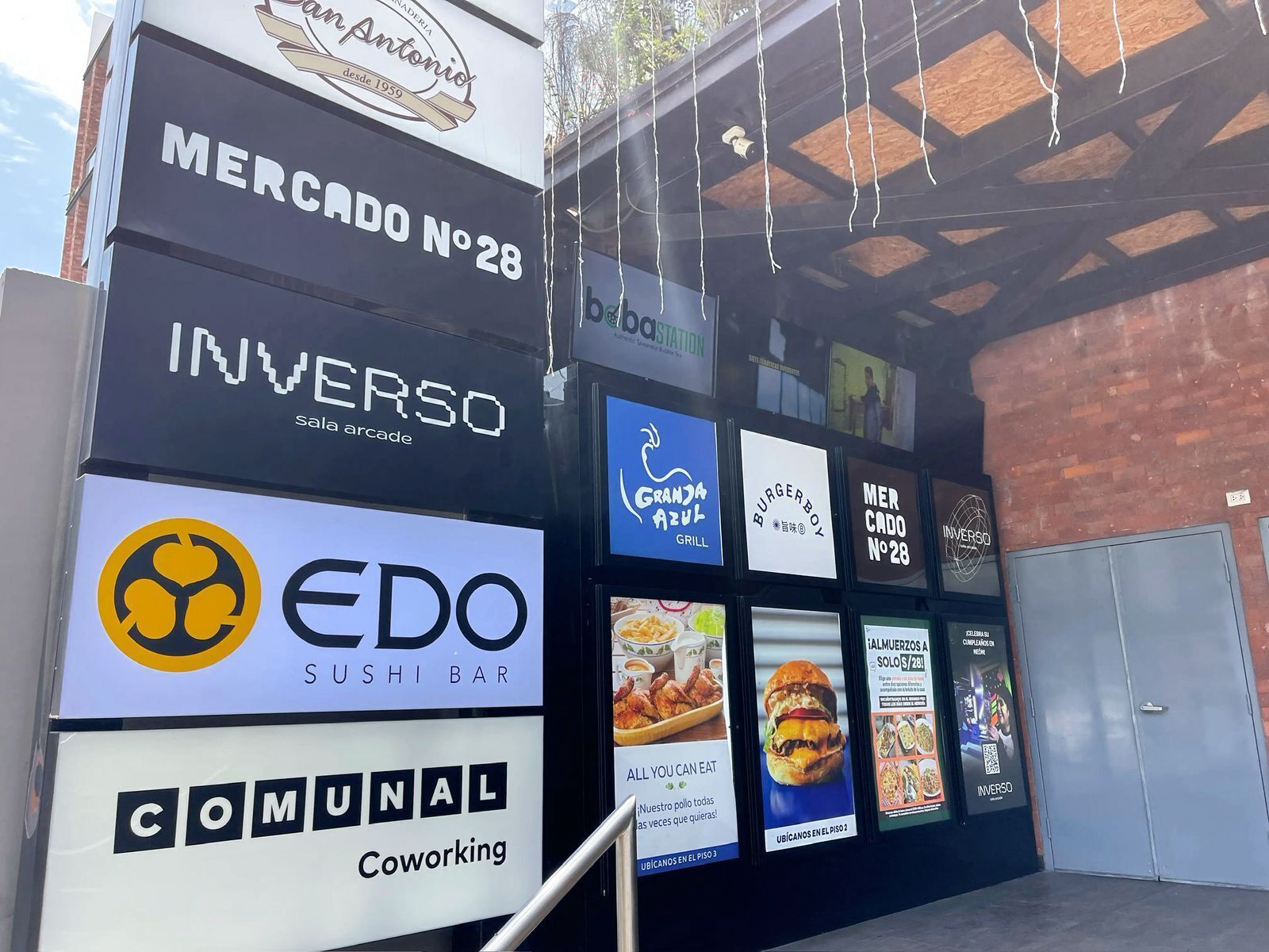 A building facade with multiple business signs, including 'MERCADO N°28', 'INVERSO', 'EDO SUSHI BAR', and 'COMUNAL Coworking'.