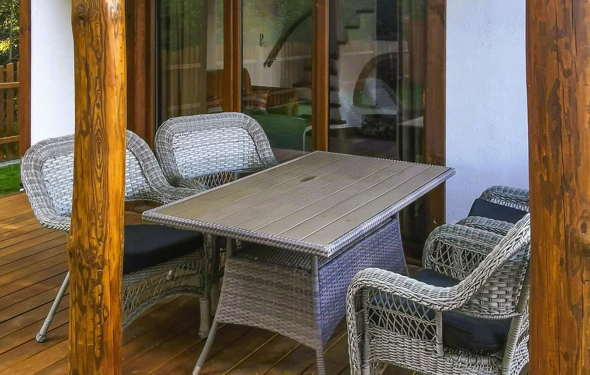 Un patio con una mesa y cuatro sillas de mimbre.