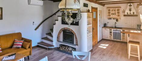 Un interior rústico con chimenea, escalera de madera y una zona de cocina.