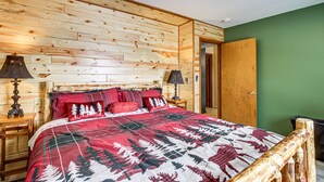 Ein schlicht eingerichtetes Schlafzimmer im Chalet-Stil mit einem Bett, zwei Nachttischen und einer Tür.