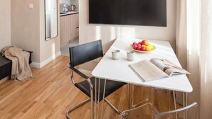A modern living space with a dining area, a kitchen, and a large TV mounted on the wall.