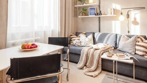 A modern living room with a sofa, a dining table with chairs, and a coffee table.